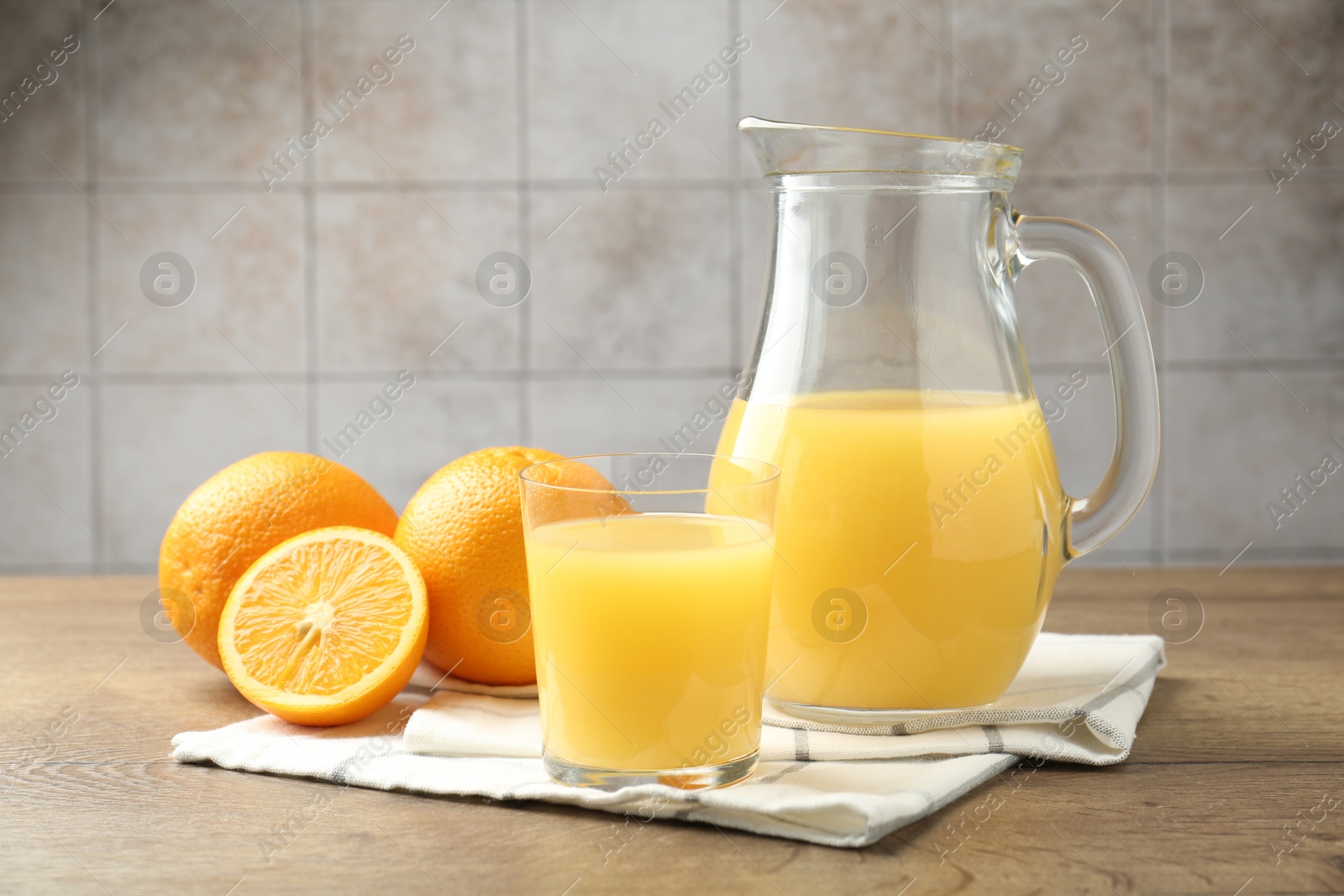 Fresh orange juice and fruits on wooden table against grey tiled wall, closeup Photo of Fresh orange juice and fruits on wooden table against grey tiled wall, closeup