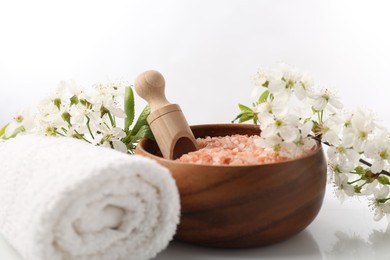Photo of Spa. Sea salt, towel and beautiful flowers on white background, closeup