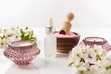 Photo of Spa composition with cosmetic products, burning candles and beautiful flowers on white background, closeup