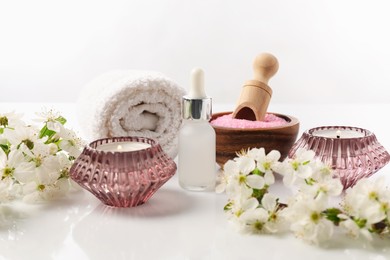 Photo of Spa composition with cosmetic products, burning candles and beautiful flowers on white background, closeup