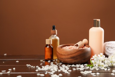 Photo of Spa composition with cosmetic products and beautiful flowers on wooden table, closeup. Space for text