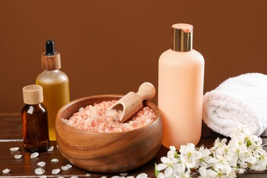 Photo of Spa composition with cosmetic products and beautiful flowers on wooden table, closeup