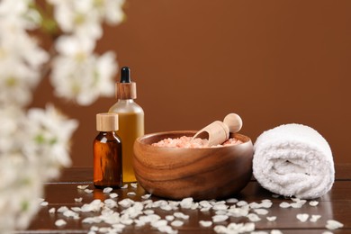 Photo of Spa composition with cosmetic products and beautiful flowers on wooden table