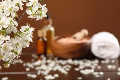 Photo of Spa composition with cosmetic products and beautiful flowers on wooden table, selective focus