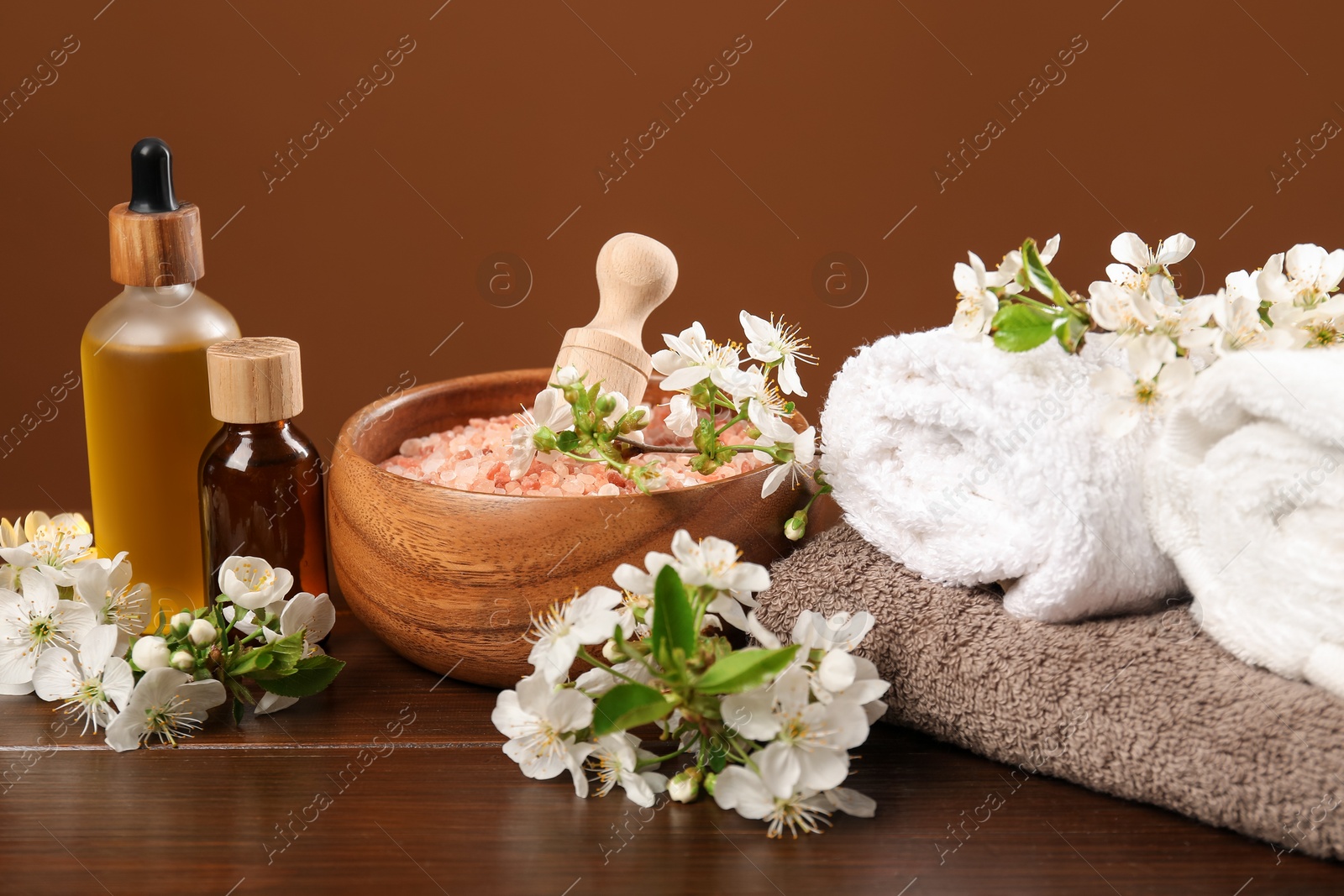 Spa composition with cosmetic products and beautiful flowers on wooden table, closeup Photo of Spa composition with cosmetic products and beautiful flowers on wooden table, closeup