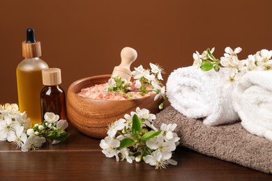 Photo of Spa composition with cosmetic products and beautiful flowers on wooden table, closeup