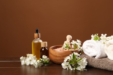 Photo of Spa composition with cosmetic products and beautiful flowers on wooden table