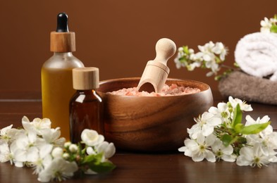 Photo of Spa composition with cosmetic products and beautiful flowers on wooden table, closeup