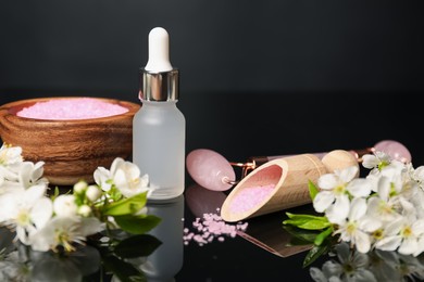 Photo of Spa composition with cosmetic products and beautiful flowers on black mirror surface, closeup