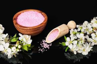 Photo of Sea salt and beautiful flowers on black mirror surface, closeup