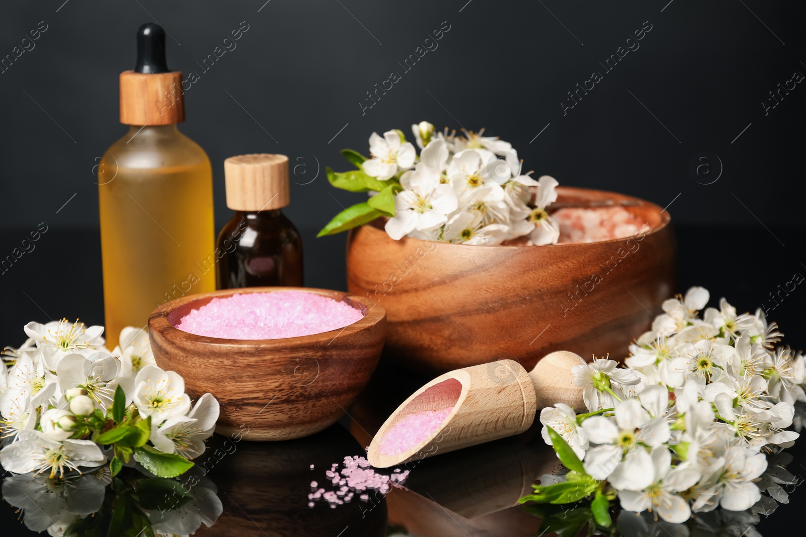 Spa composition with cosmetic products and beautiful flowers on black mirror surface, closeup Photo of Spa composition with cosmetic products and beautiful flowers on black mirror surface, closeup
