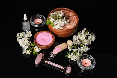 Photo of Spa composition with cosmetic products, burning candles and beautiful flowers on black mirror surface, above view