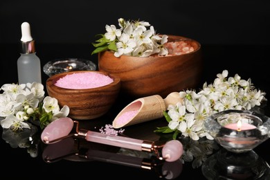 Photo of Spa composition with cosmetic products and beautiful flowers on black mirror surface, closeup