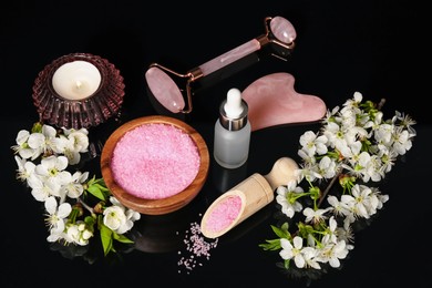 Photo of Spa composition with cosmetic products, burning candle and beautiful flowers on black mirror surface, above view