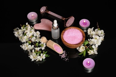 Photo of Spa composition with cosmetic products, burning candles and beautiful flowers on black mirror surface, above view
