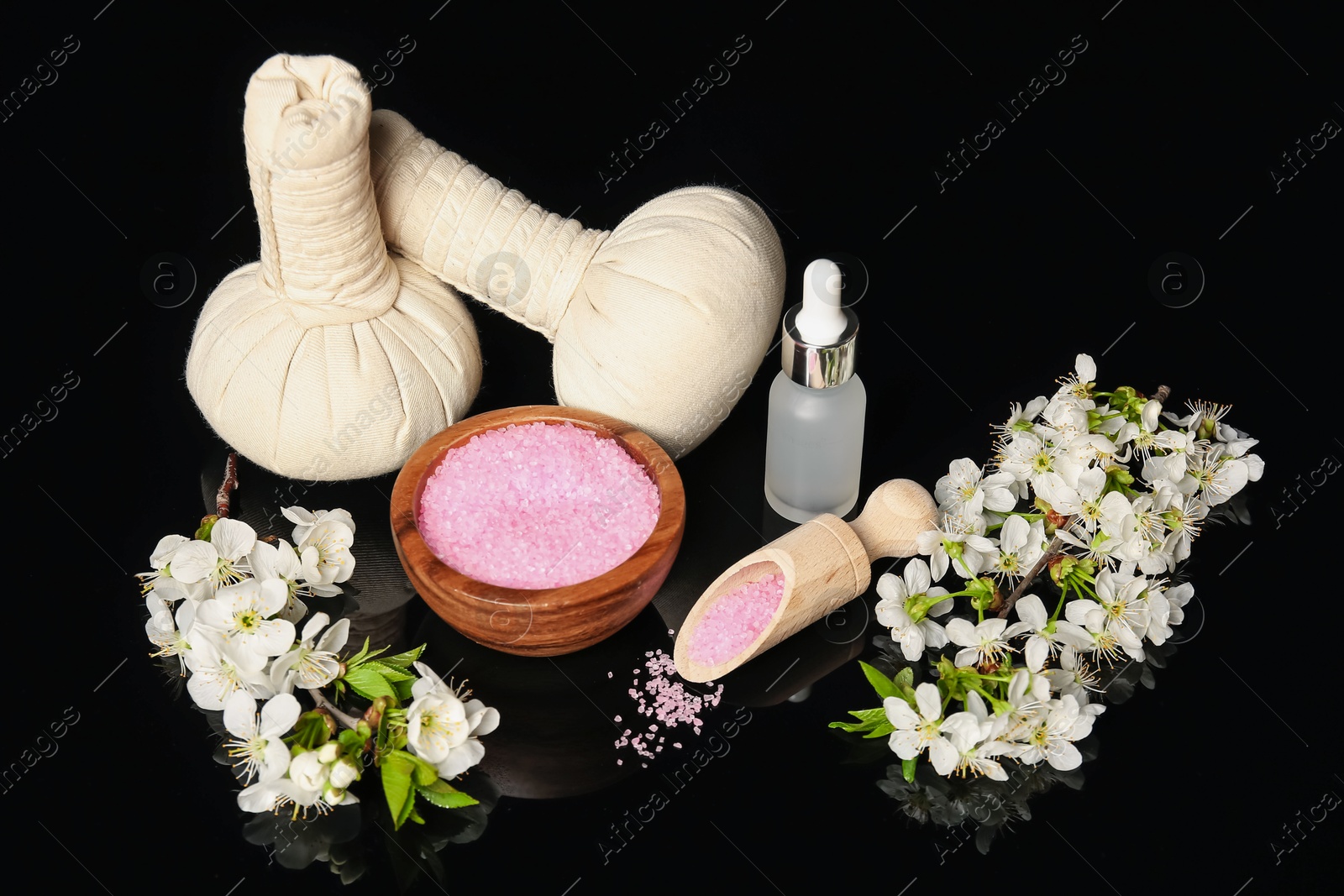 Spa composition with cosmetic products and beautiful flowers on black mirror surface Photo of Spa composition with cosmetic products and beautiful flowers on black mirror surface