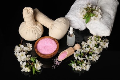 Photo of Spa composition with cosmetic products and beautiful flowers on black mirror surface, above view