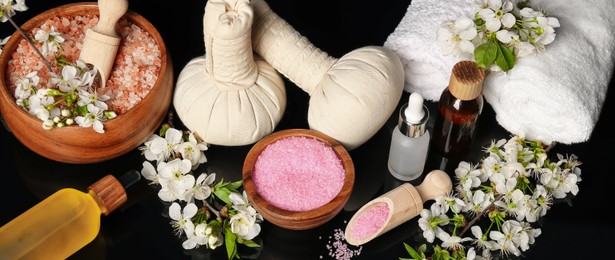 Photo of Spa composition with cosmetic products and beautiful flowers on black mirror surface