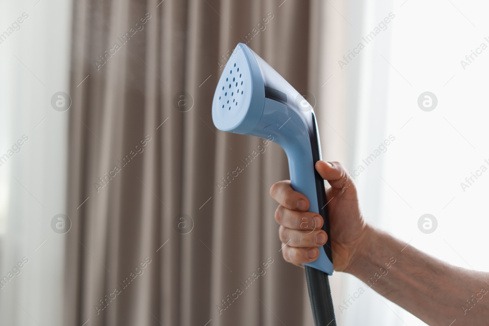Photo of Man with stand steamer at home, closeup