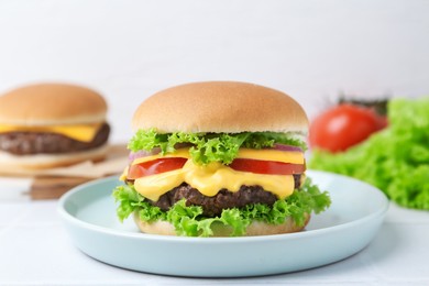 Photo of Tasty cheeseburger with lettuce and tomatoes on white table, closeup