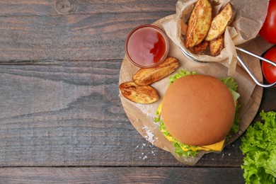Photo of Tasty cheeseburger with potato wedges and ketchup on wooden table, flat lay. Space for text