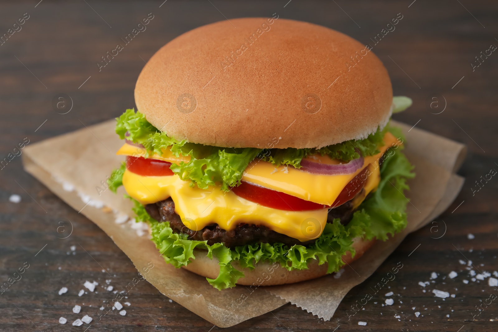 Tasty cheeseburger with lettuce and tomatoes on wooden table, closeup Photo of Tasty cheeseburger with lettuce and tomatoes on wooden table, closeup