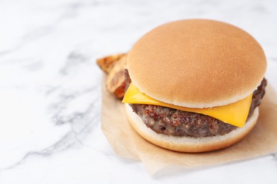 Photo of Tasty cheeseburger with potato wedges on white marble table, closeup. Space for text