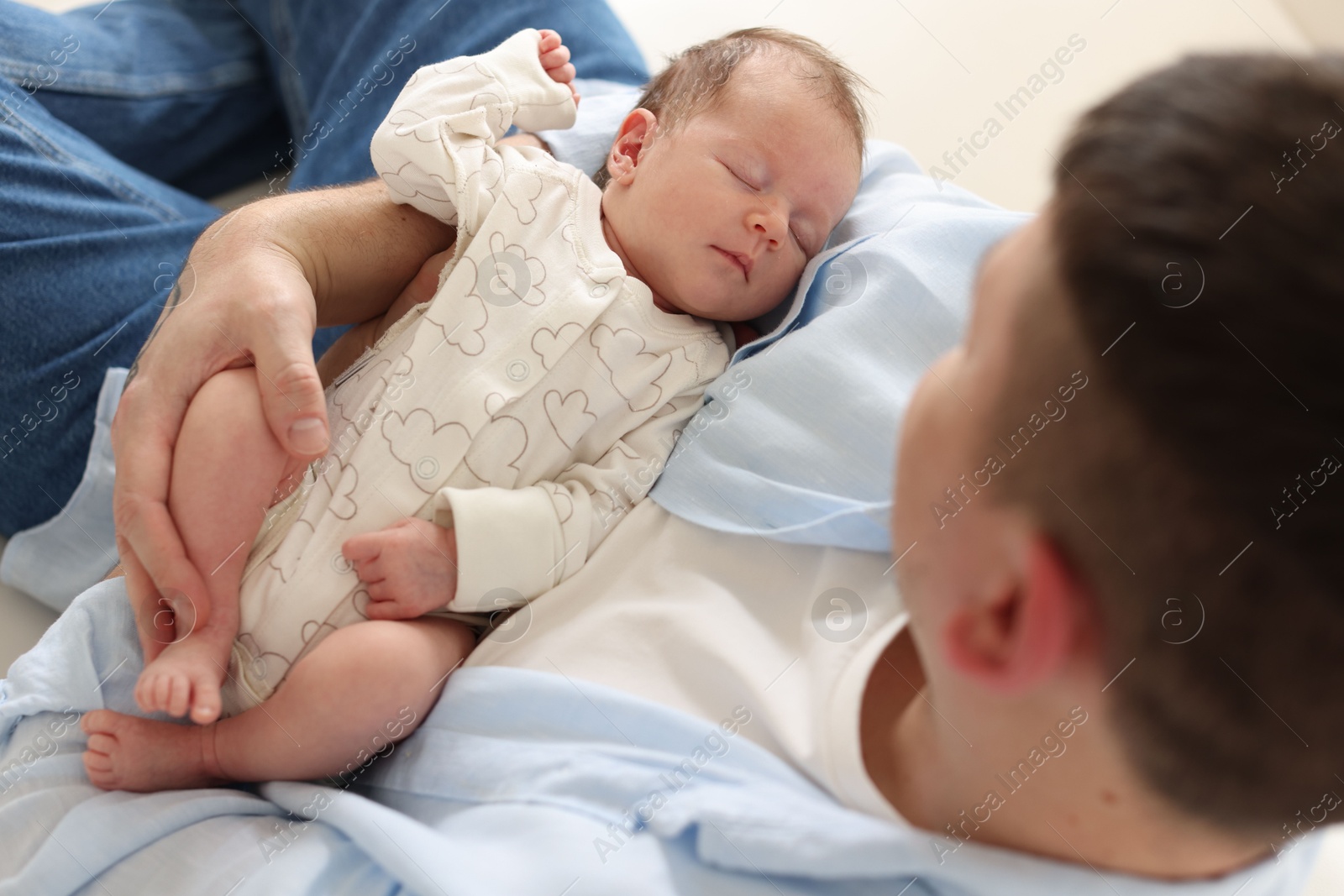 Photo of Father with his cute newborn baby indoors, above view