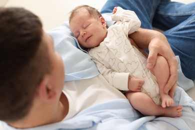 Photo of Father with his cute newborn baby indoors, above view