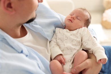 Photo of Father with his cute newborn baby indoors, closeup