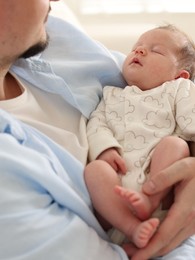 Photo of Father with his cute newborn baby indoors, closeup