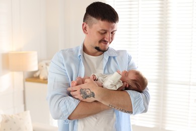 Photo of Father with his cute newborn baby indoors
