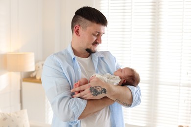 Photo of Father with his cute newborn baby indoors