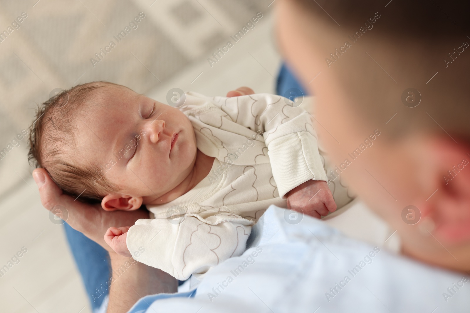 Photo of Father with his cute newborn baby indoors, above view