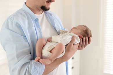 Photo of Father with his cute newborn baby indoors, closeup