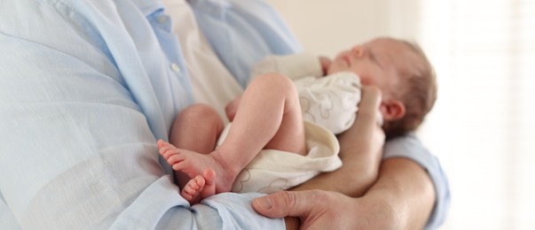 Photo of Father with his cute newborn baby indoors, closeup