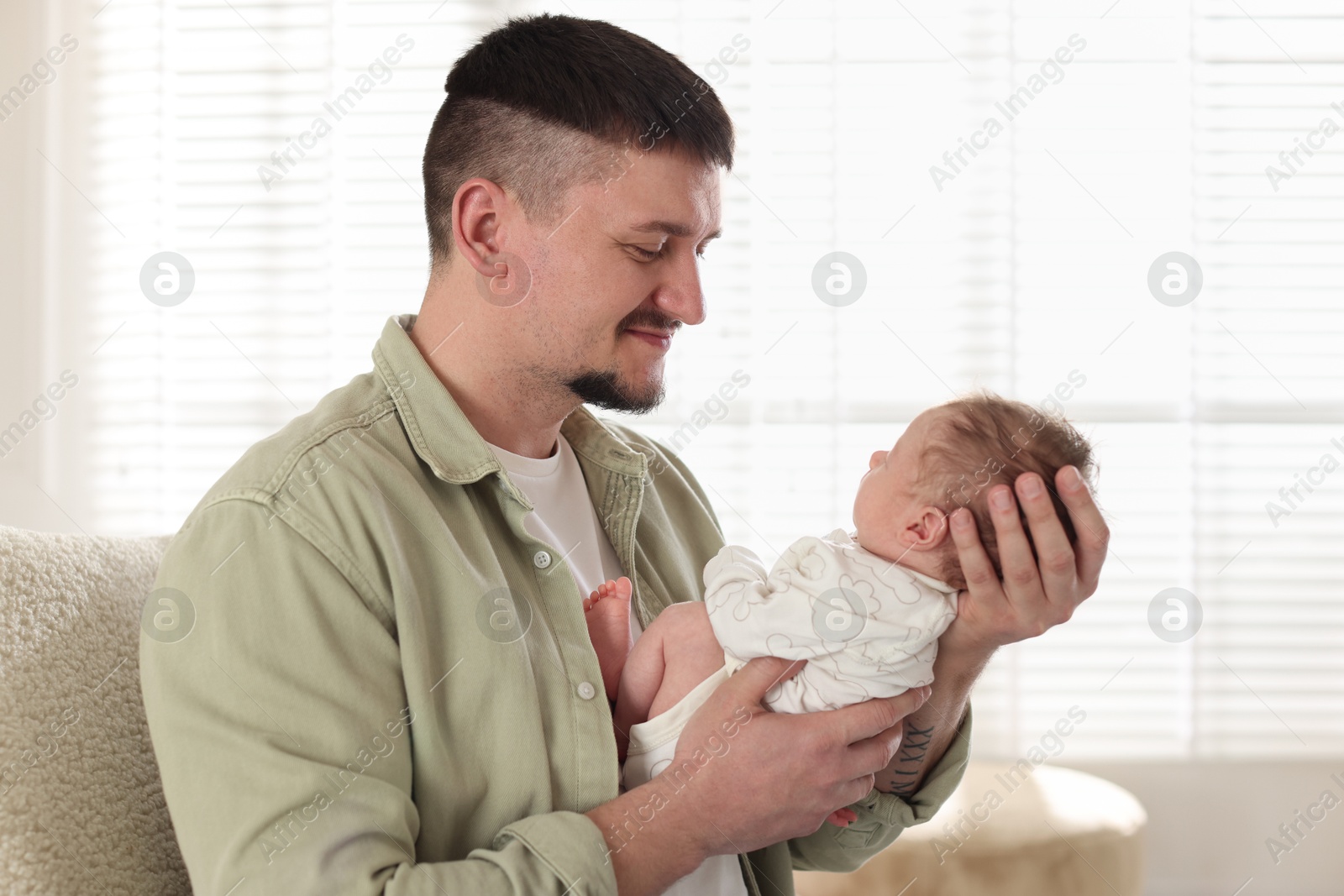 Father with his cute newborn baby in armchair indoors Photo of Father with his cute newborn baby in armchair indoors