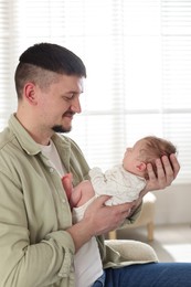 Photo of Father with his cute newborn baby indoors