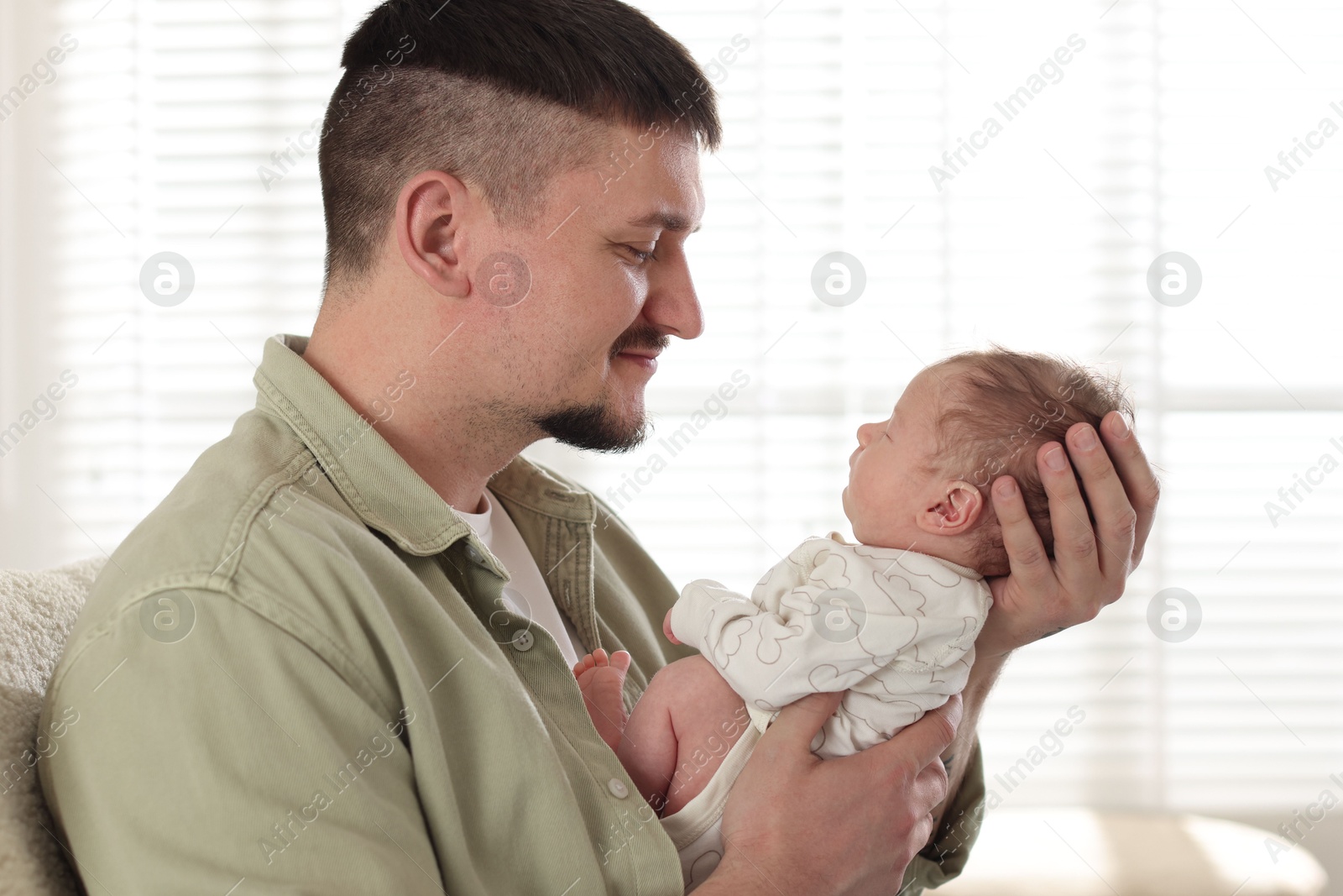 Father with his cute newborn baby indoors Photo of Father with his cute newborn baby indoors