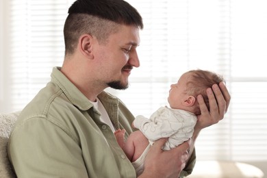 Photo of Father with his cute newborn baby indoors
