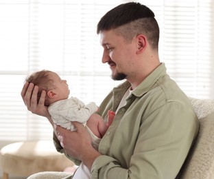 Photo of Father with his cute newborn baby indoors
