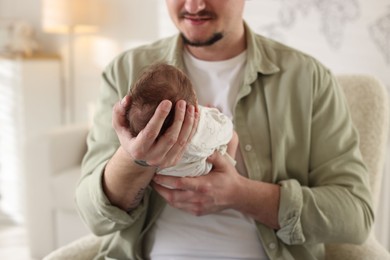 Photo of Father with his cute newborn baby in armchair indoors, closeup