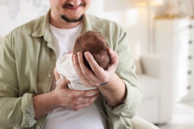 Photo of Father with his cute newborn baby indoors, closeup. Space for text