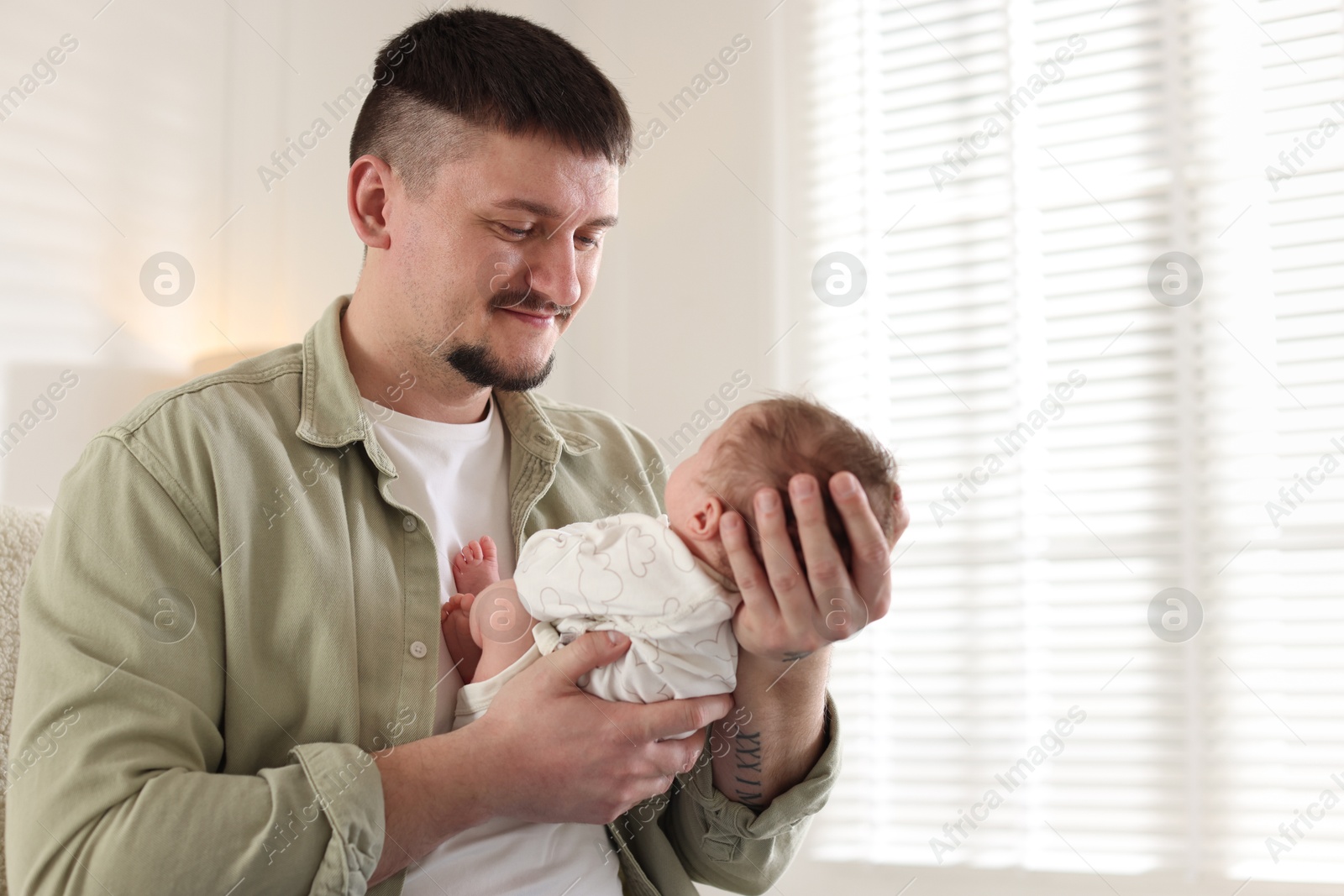 Father with his cute newborn baby indoors, space for text Photo of Father with his cute newborn baby indoors, space for text