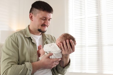 Photo of Father with his cute newborn baby indoors, space for text