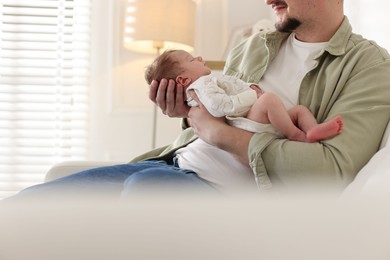 Photo of Father with his cute newborn baby on sofa indoors, closeup. Space for text