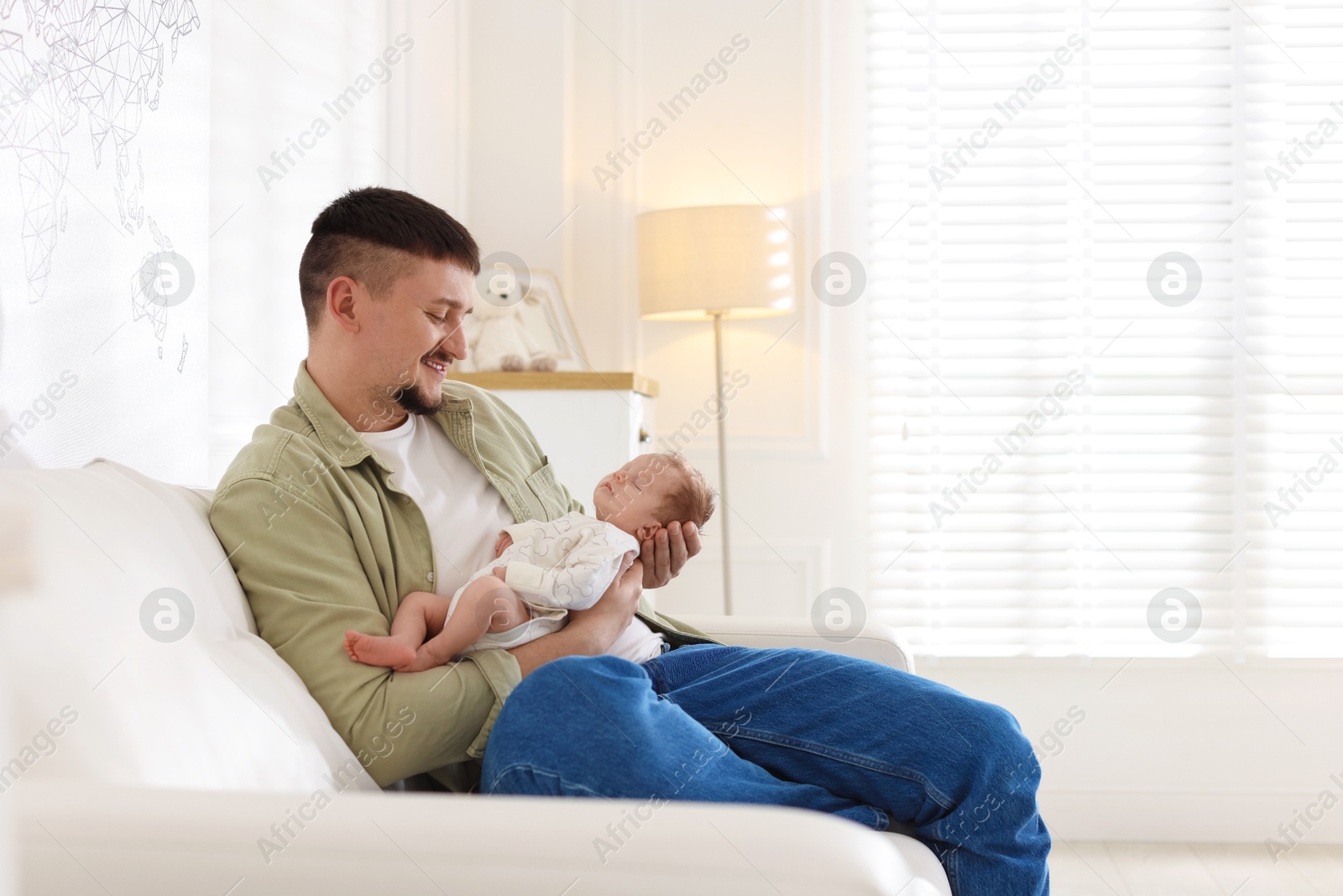 Photo of Father with his cute newborn baby on sofa indoors, space for text