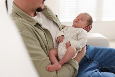 Photo of Father with his cute newborn baby on sofa indoors, closeup