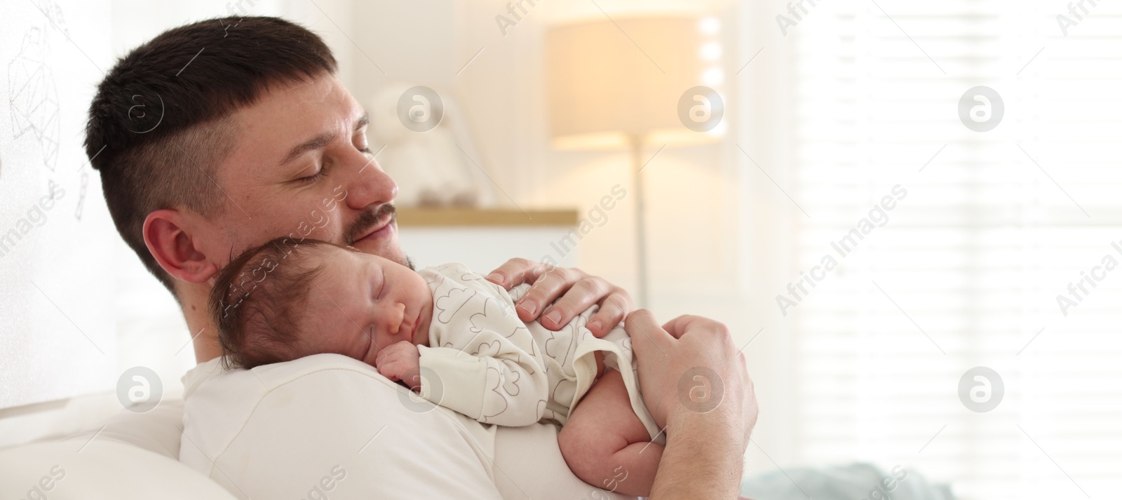 Photo of Father with his cute newborn baby on sofa indoors, space for text