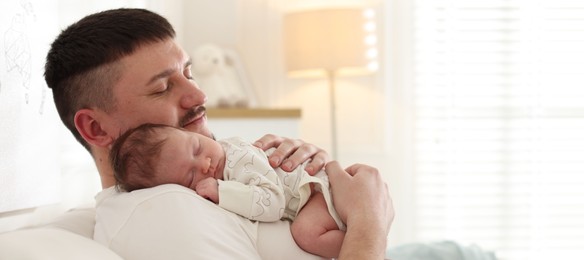 Photo of Father with his cute newborn baby on sofa indoors, space for text